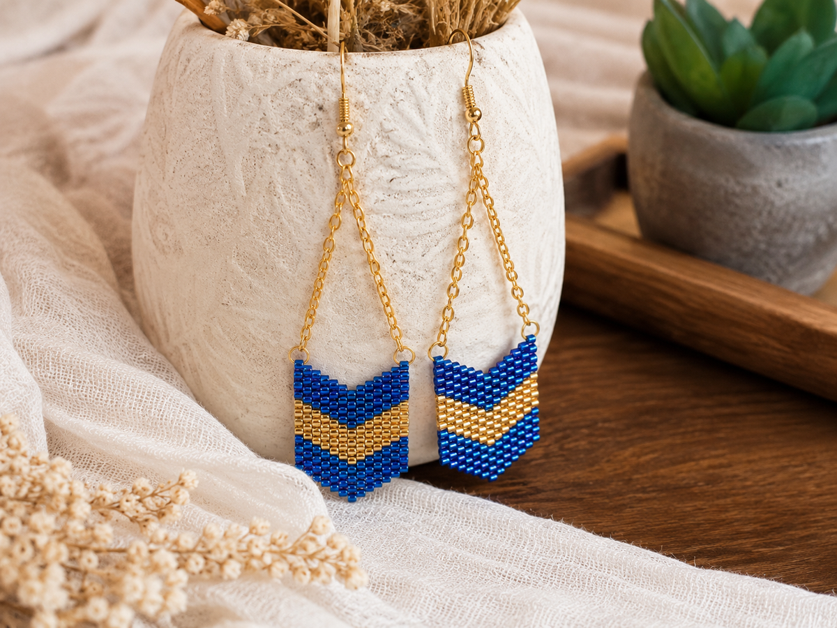 Boucles d’oreilles bohèmes bleu et doré en perles Miyuki présentées dans une ambiance chaleureuse.