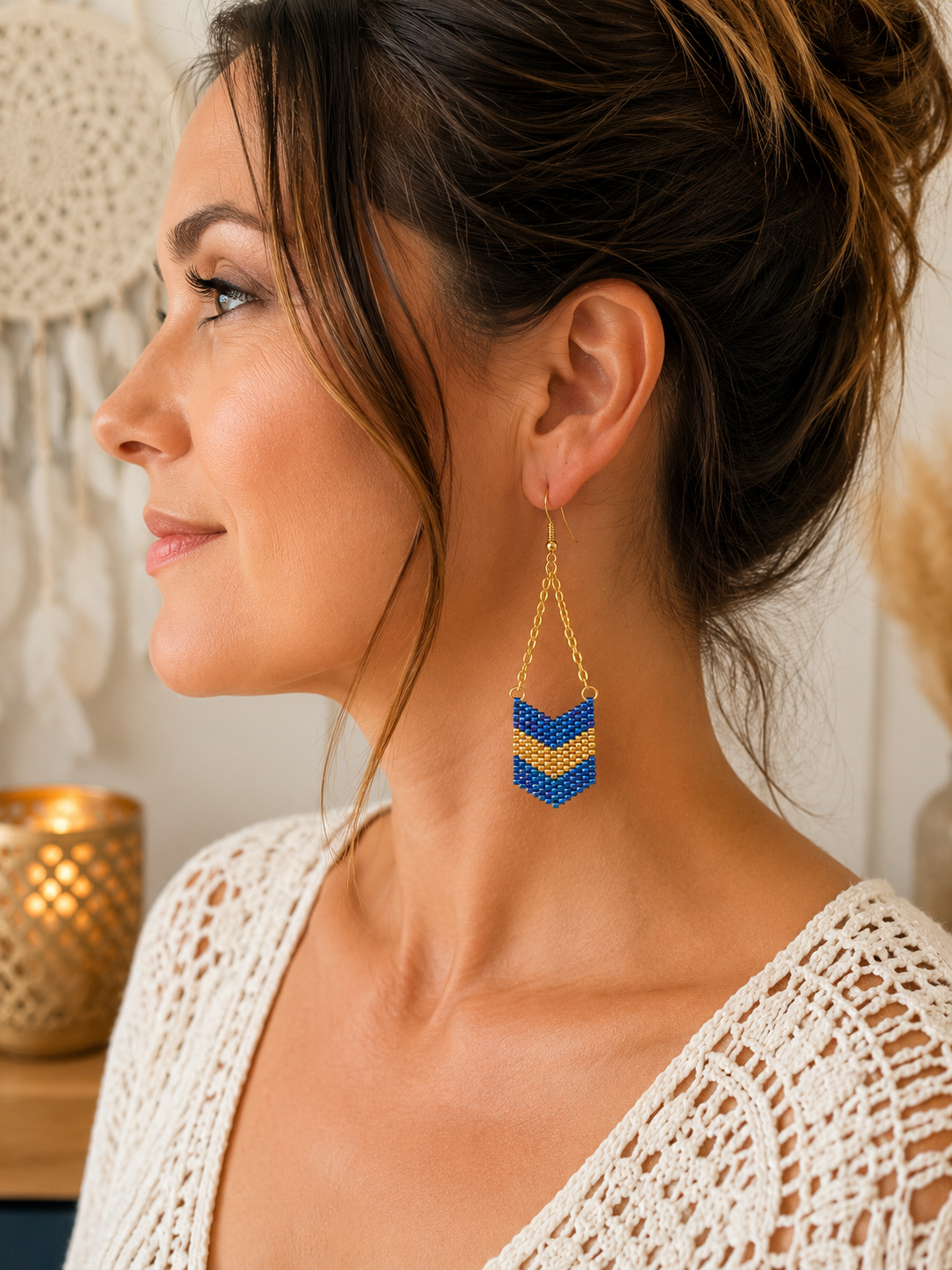 Boucle d’oreille pendante bleu et doré en perles Miyuki tissées à la main portée à l’oreille.
