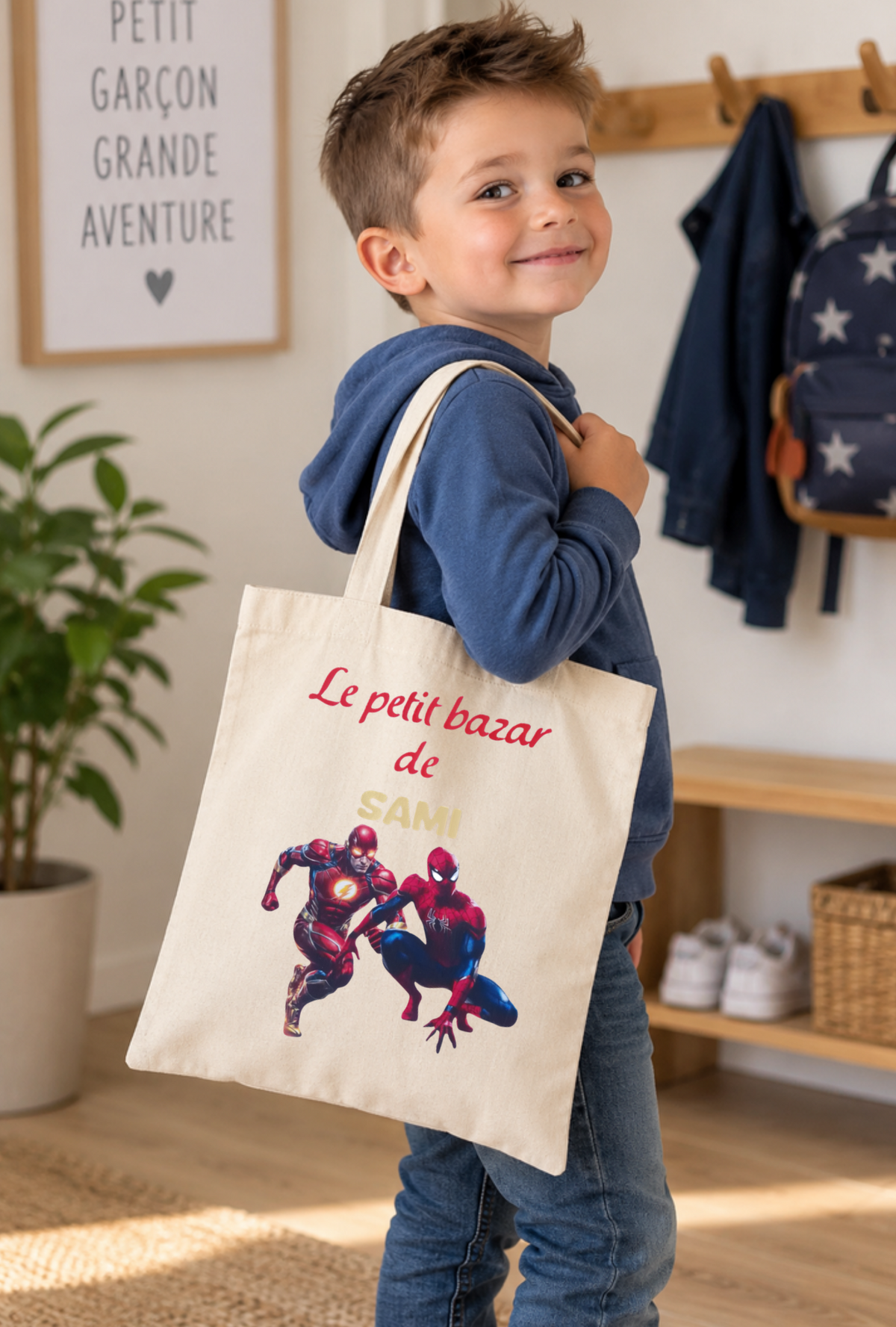 Tote bag beige personnalisé avec prénom pour enfant, porté à l'épaule par un petit garçon dans un univers de super-héros, modèle Le petit bazar de Sami.