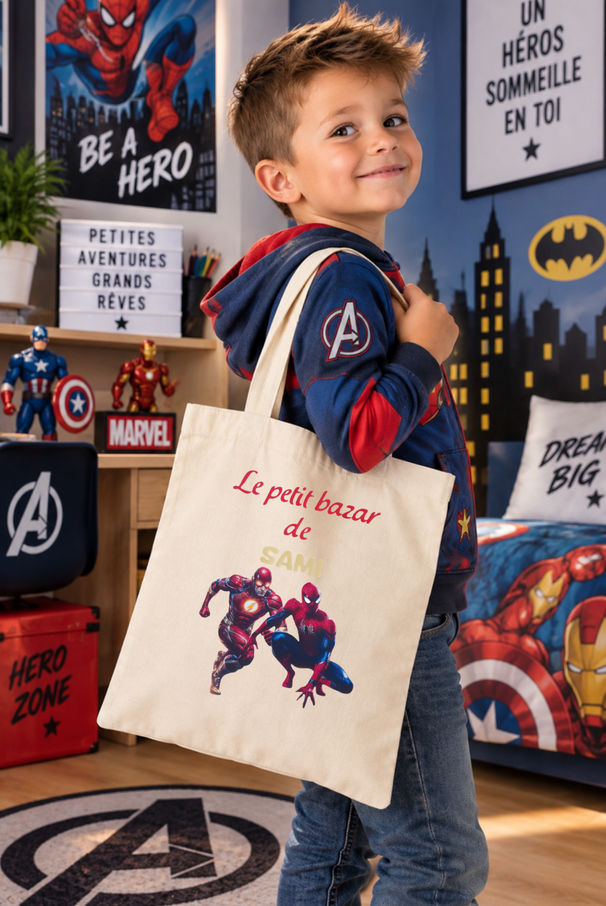 Tote bag beige personnalisé avec prénom pour enfant, porté à l'épaule par un petit garçon dans un univers de super-héros, modèle Le petit bazar de Sami.