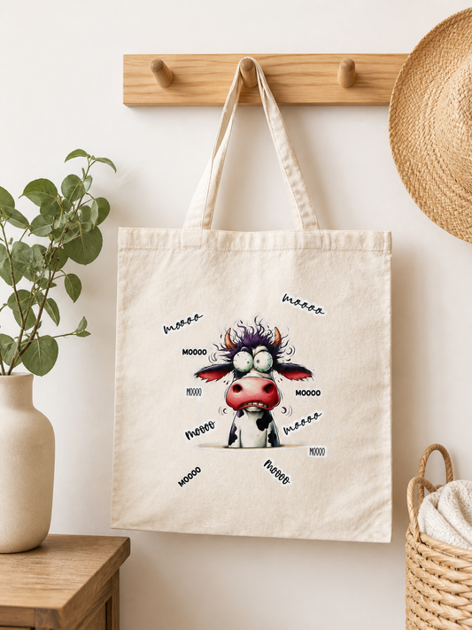 Tote bag en coton avec illustration humoristique d’une vache folle entourée de texte MOOO accroché porte manteau