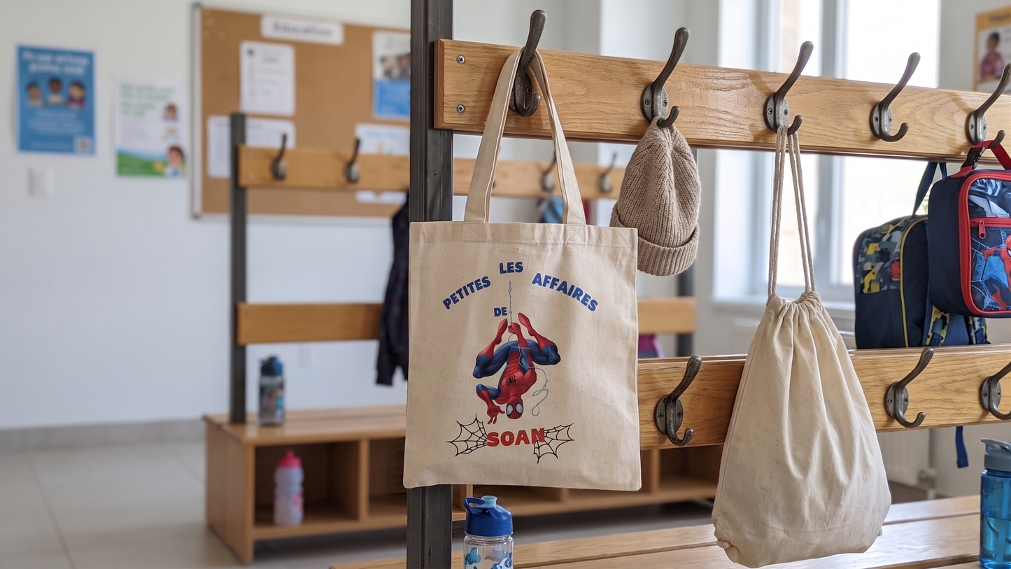 Tote bag enfant personnalisé avec prénom et illustration Spiderman, suspendu à un porte manteau d'école