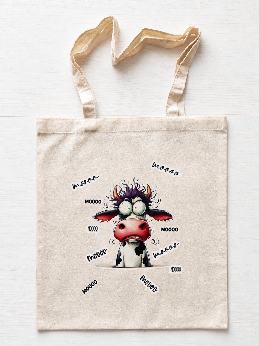 Tote bag en coton avec illustration humoristique d’une vache folle entourée de texte MOOO fond blanc

